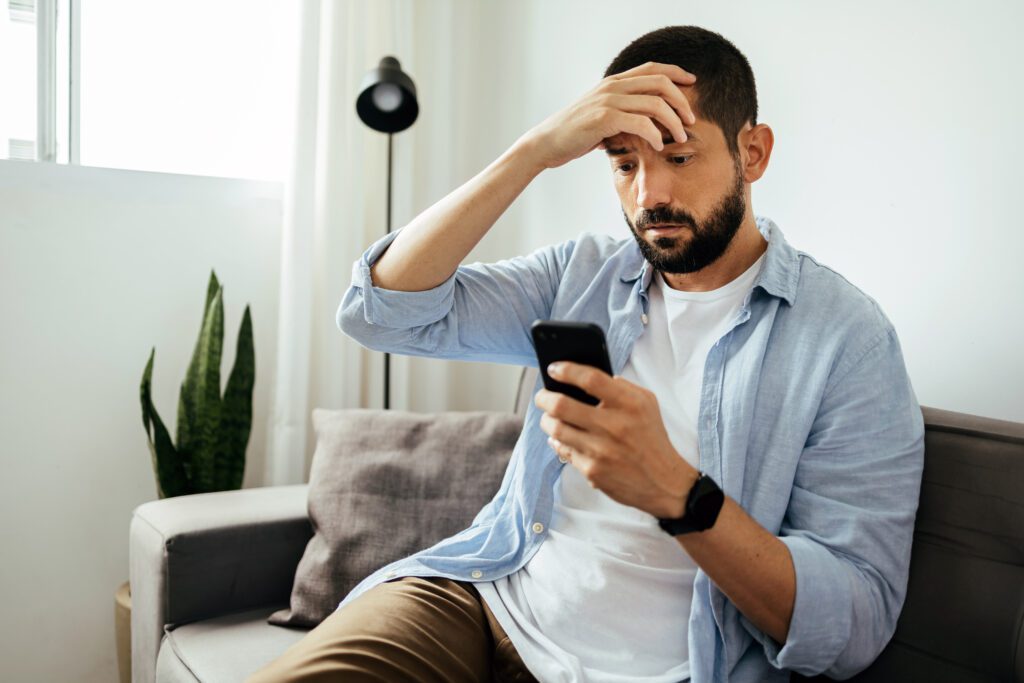 A man looks at his phone and is worried at what he's reading.